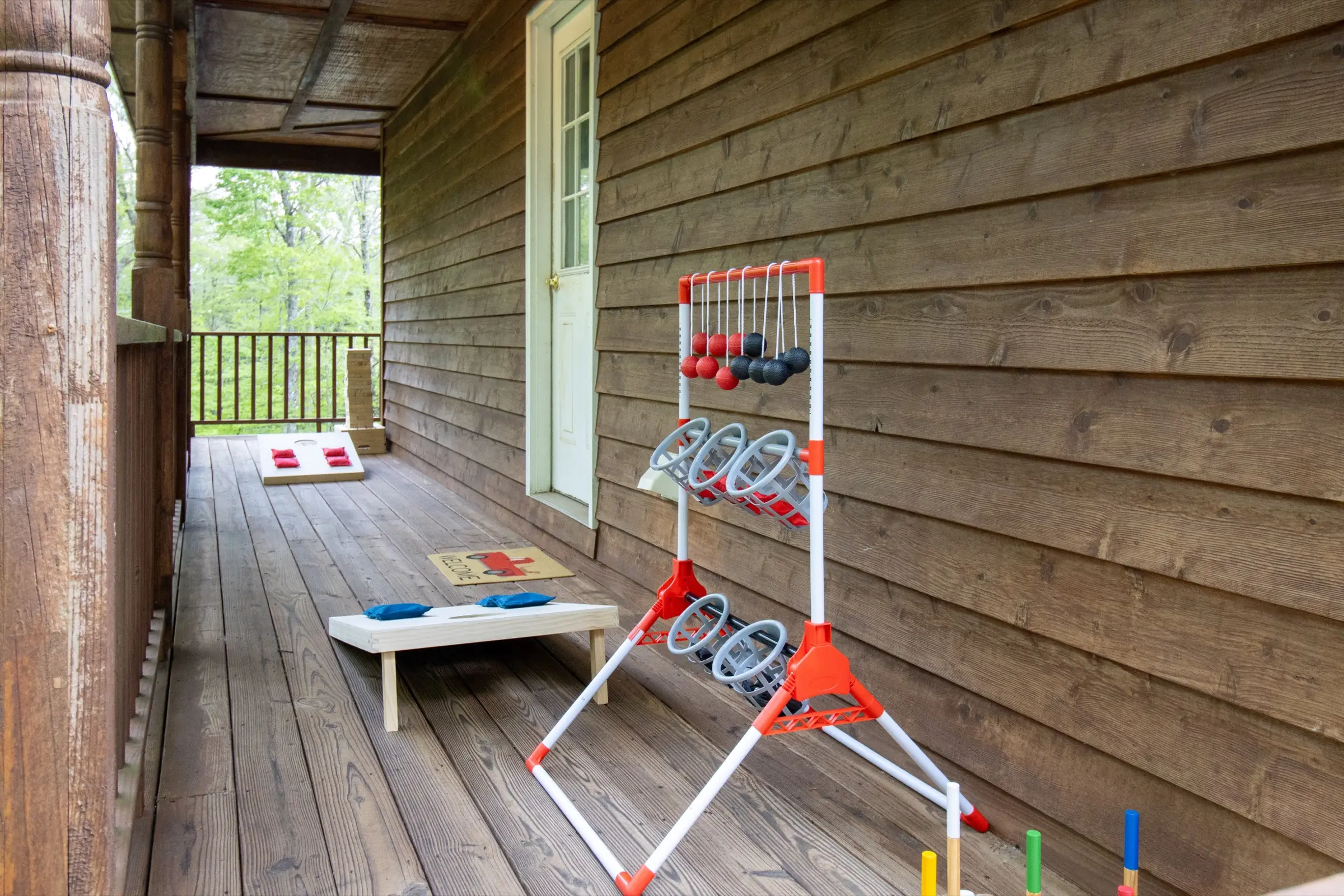 Outdoor games on the covered lower porch, including cornhole, ladder toss and croquet.