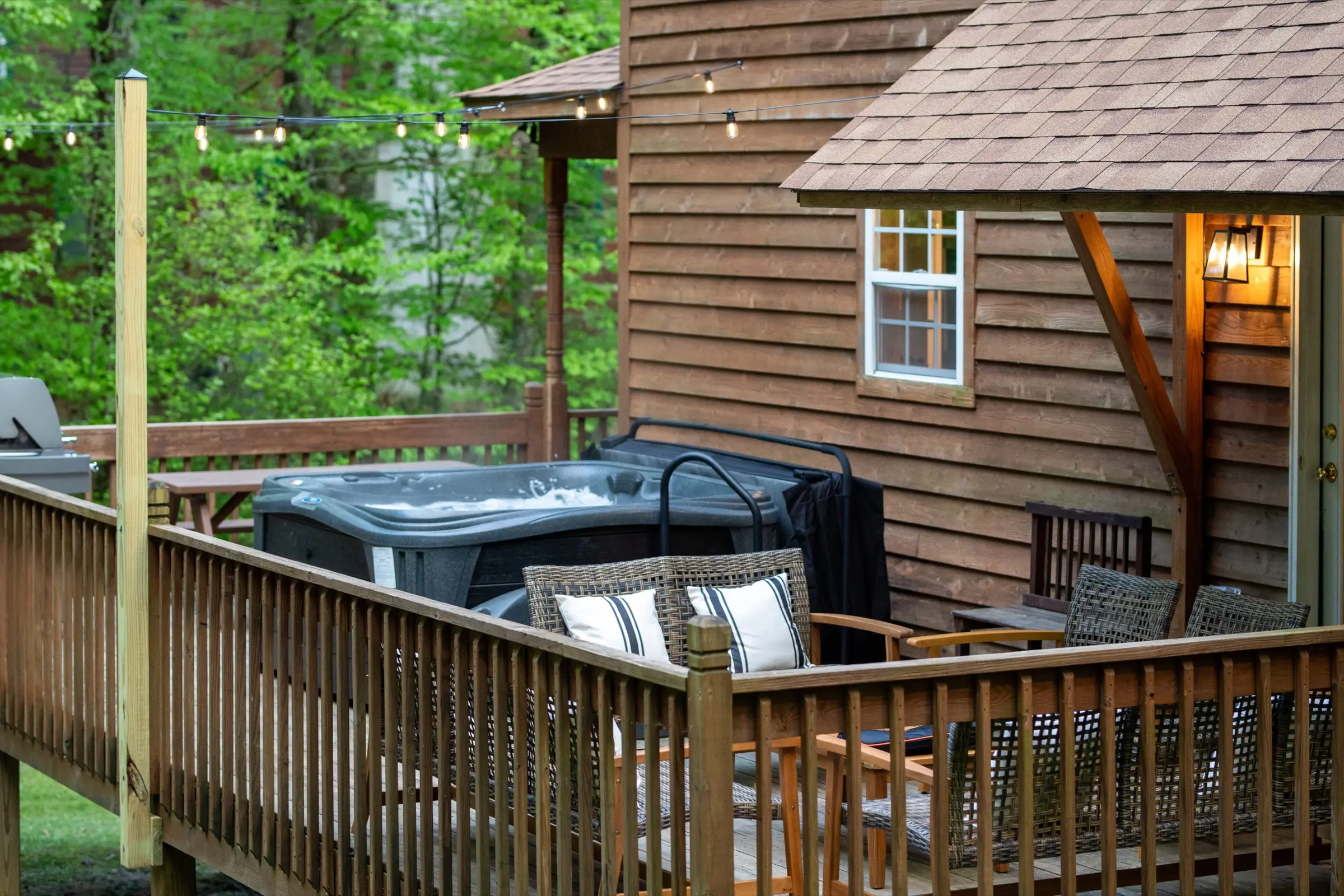 The covered hot tub on the rear deck, with the wooded slope beyond.