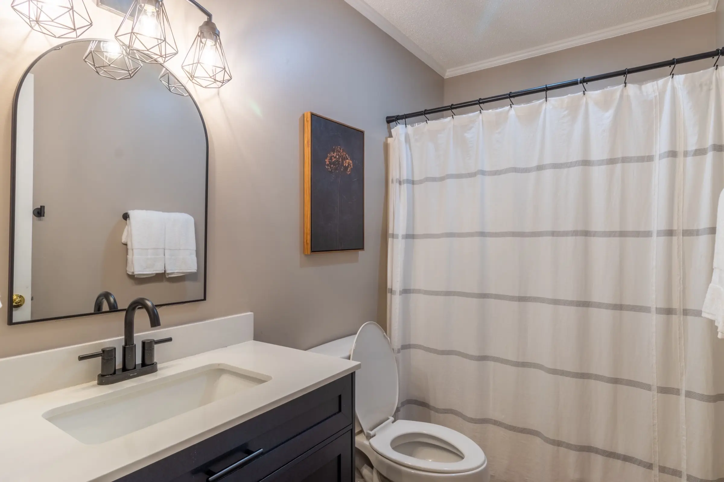 The downstairs full bathroom, with a single vanity and a combination tub and shower behind a curtain.