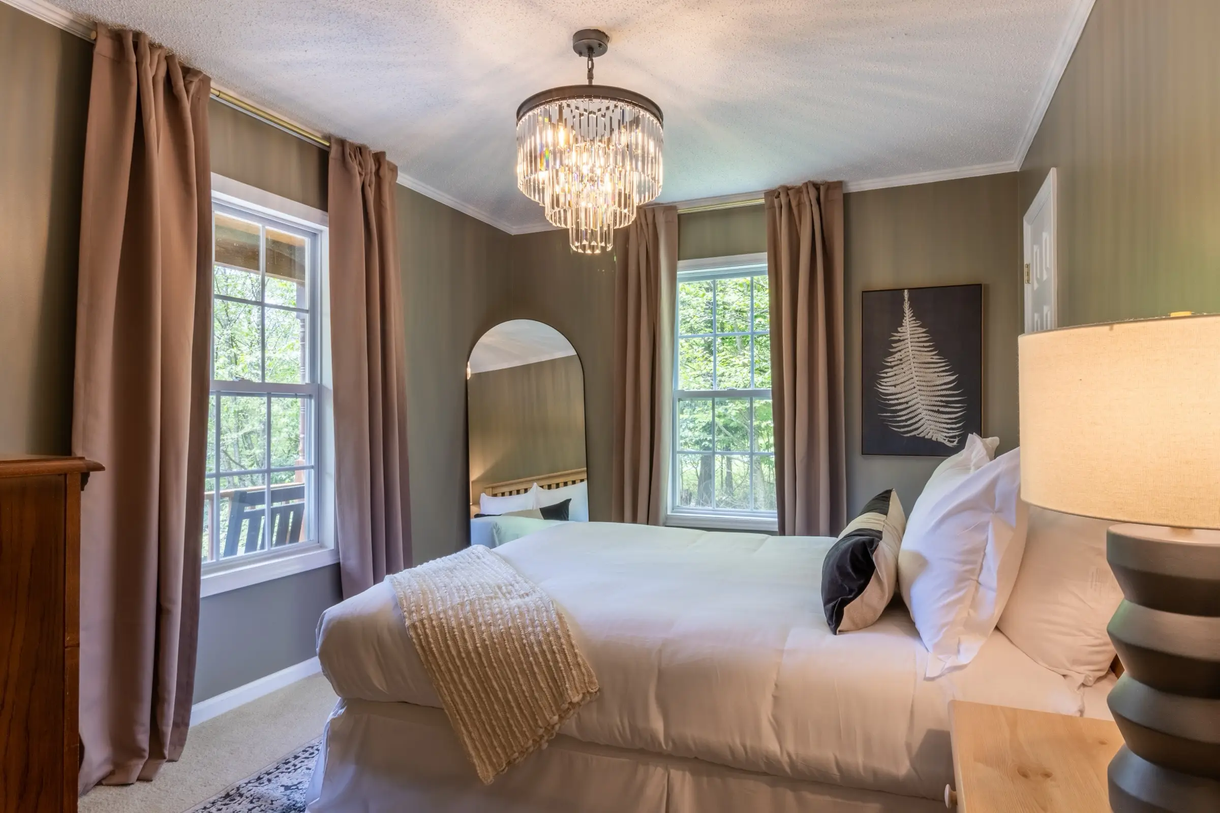 Downstairs bedroom 1, with a queen bed and framed botanical prints between two windows.