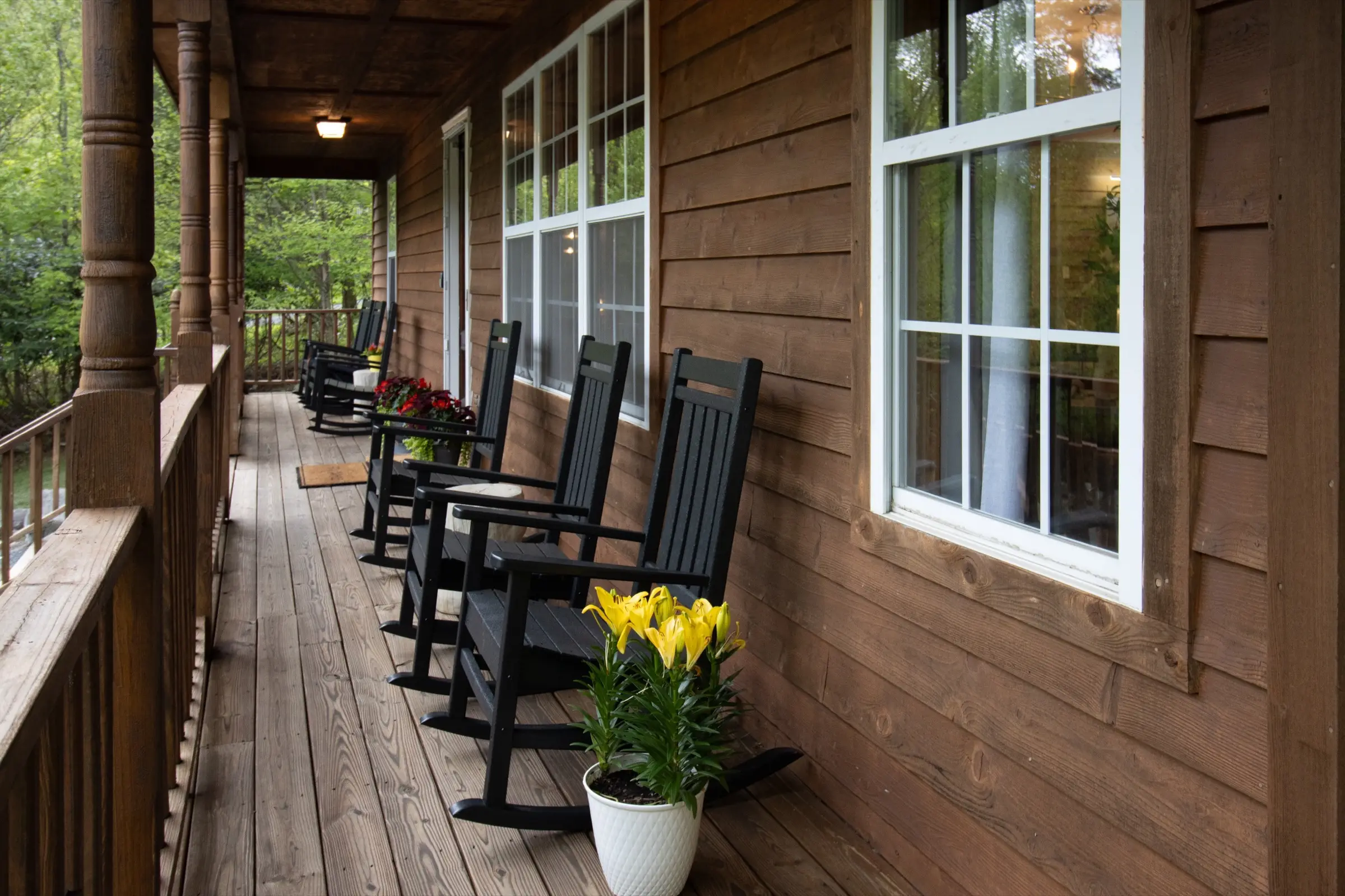The covered front porch, with black rocking chairs and potted flowers.