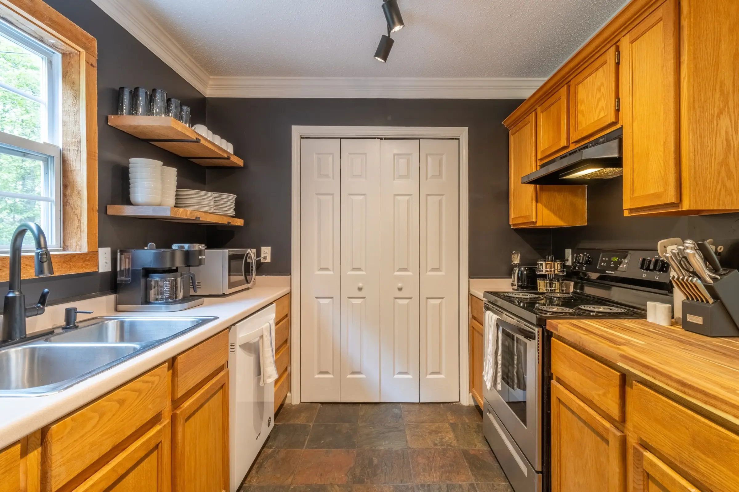 The kitchen looking toward the laundry doors, with the range and dishwasher.