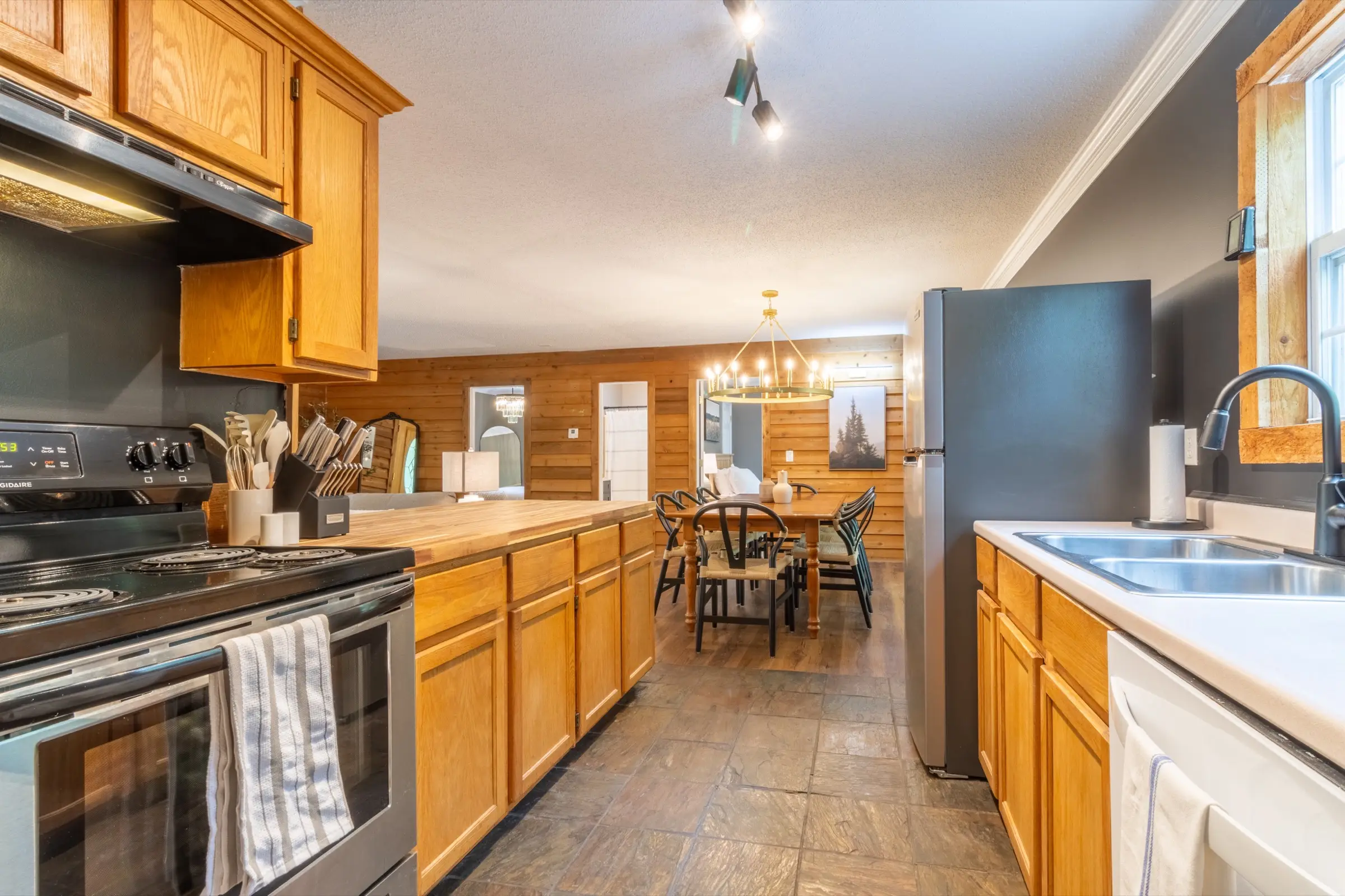 The kitchen, with refrigerator, open shelving, coffee maker and a butcher-block island with three stools.