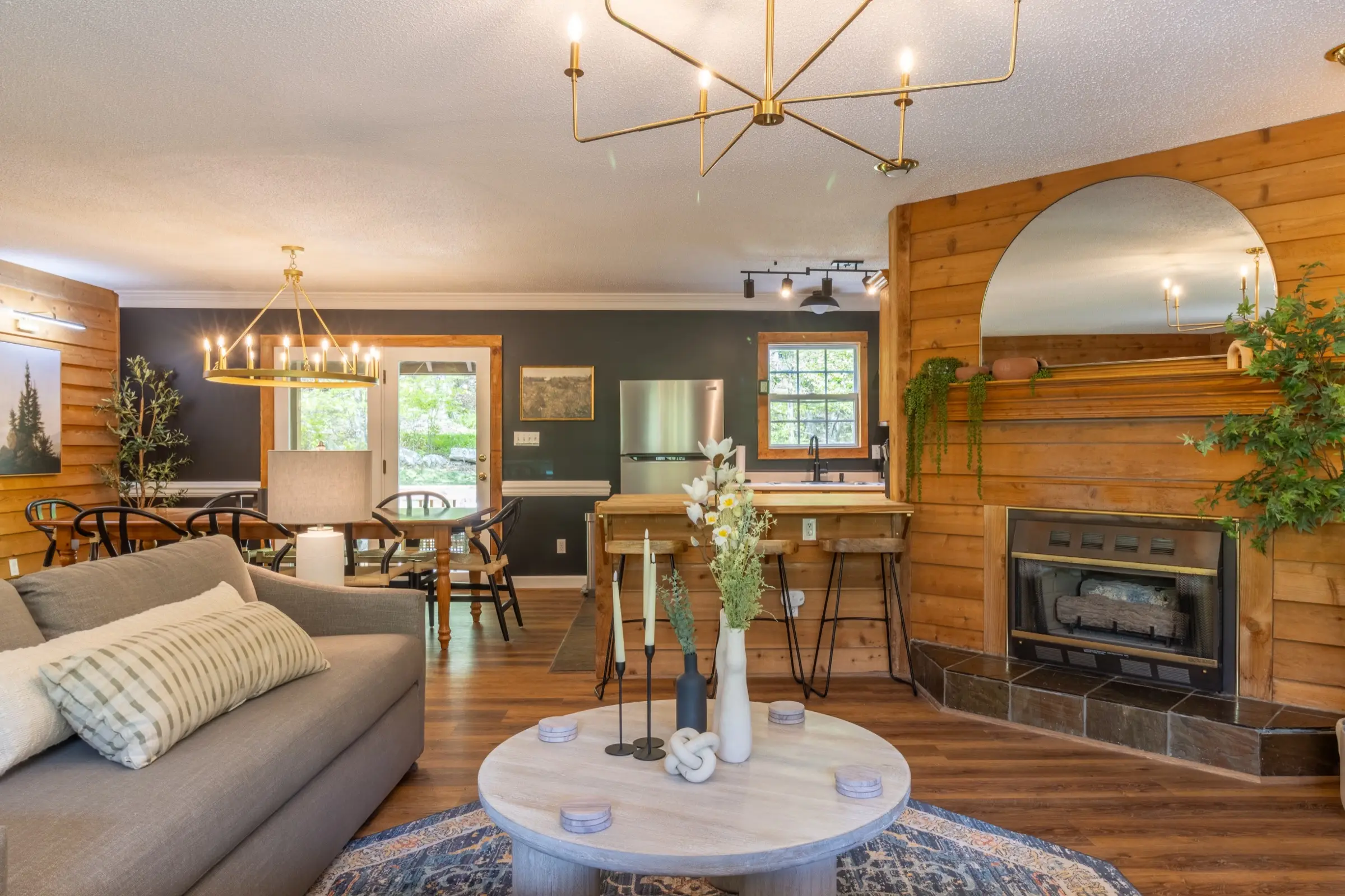 The open main level, with the living room fireplace connecting through to the dining table and kitchen beyond.