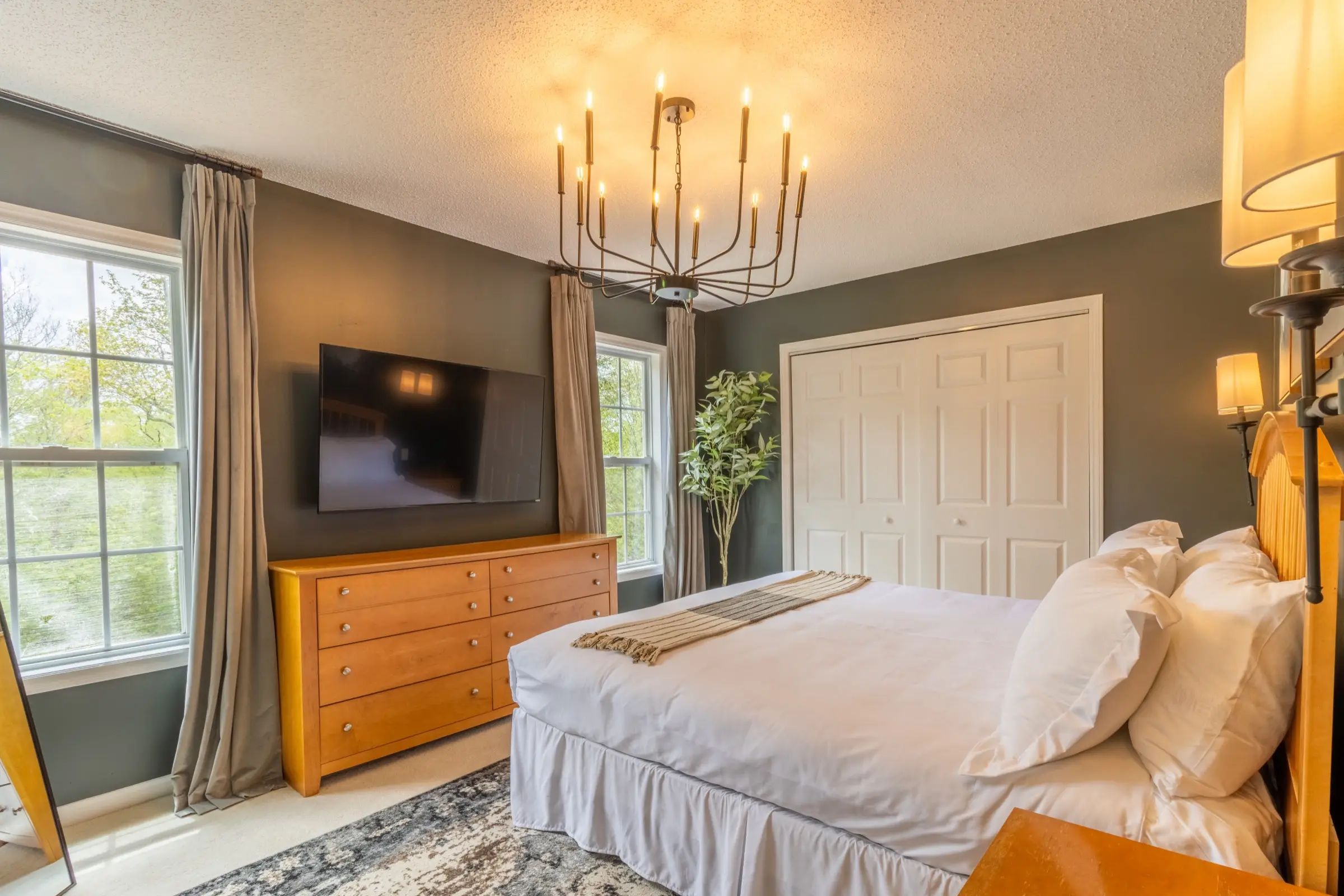 The Primary Bedroom, with a king bed, wall sconces and framed mountain prints.