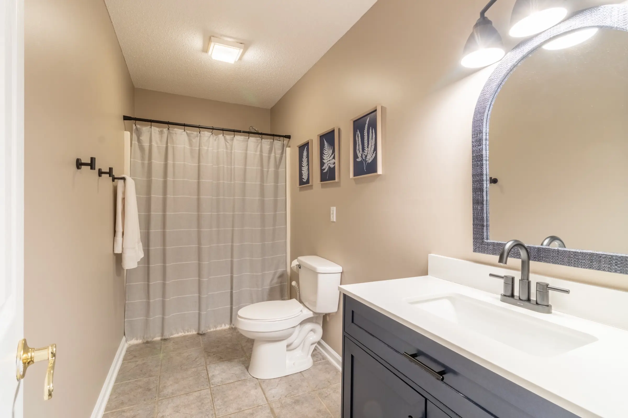 Upstairs bathroom 1, with a combination tub and shower and framed botanical prints.